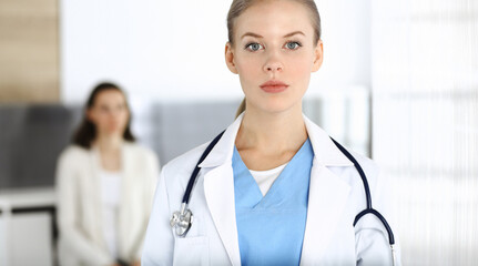 Woman - doctor standing in clinic. Physician at work, studio portrait. Medicine and health care concept