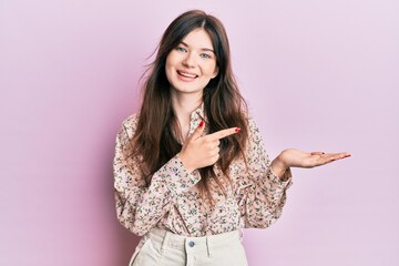 Wall Mural - Young beautiful caucasian girl wearing elegant clothes amazed and smiling to the camera while presenting with hand and pointing with finger.