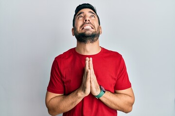 Canvas Print - Young hispanic man wearing casual clothes begging and praying with hands together with hope expression on face very emotional and worried. begging.