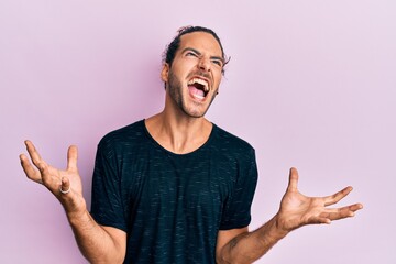 Sticker - Young handsome man with long hair wearing casual clothes crazy and mad shouting and yelling with aggressive expression and arms raised. frustration concept.