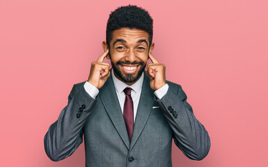 Sticker - Young african american man wearing business clothes covering ears with fingers with annoyed expression for the noise of loud music. deaf concept.