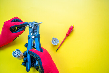 Wall Mural - Electrician peeling off insulation from wires - closeup on hands and pliers