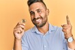 © Krakenimages.com - Handsome man with beard holding virtual currency bitcoin surprised with an idea or question pointing finger with happy face, number one