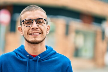 Young hispanic man smiling happy standing at the city.