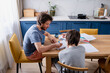 © Елена Григорович - Teenager boy doing school lessons at home. Dad helping solve difficult math problems. Problems and difficulties of home education