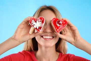 Wall Mural - Concept of choice between healthy and junk food. Woman with cakes on light blue background