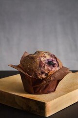 Vertical closeup shot of a delicious blueberry muffin on a chopping board with a bl