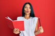 © Krakenimages.com - Young african american woman holding book and pencil looking at the camera blowing a kiss being lovely and sexy. love expression.