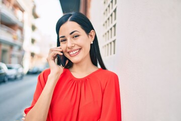 Wall Mural - Young latin girl smiling happy talking on the smartphone at the city.