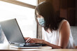 © cocorattanakorn - Asian young woman is wearing mask prevent for civid-19 and online working with laptop in office. She is searching information on internet at coffee shop. Businesswoman work with technology concept.