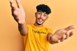 © Krakenimages.com - Young arab handsome man wearing tshirt with happiness word message looking at the camera smiling with open arms for hug. cheerful expression embracing happiness.