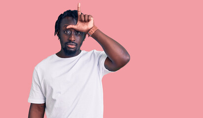 Poster - Young african american man with braids wearing casual white tshirt making fun of people with fingers on forehead doing loser gesture mocking and insulting.