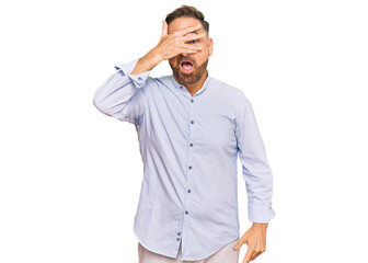 Poster - Handsome middle age man wearing business shirt peeking in shock covering face and eyes with hand, looking through fingers with embarrassed expression.