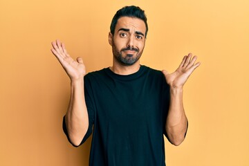 Canvas Print - Young hispanic man wearing casual clothes clueless and confused with open arms, no idea and doubtful face.