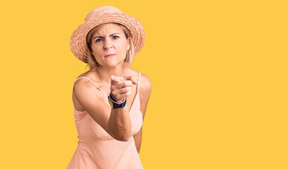 Poster - Young blonde woman wearing summer hat pointing displeased and frustrated to the camera, angry and furious with you