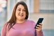 © Krakenimages.com - Young plus size woman smiling happy using smartphone at the city.