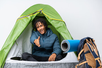 Sticker - Young african american man inside a camping green tent shaking hands for closing a good deal