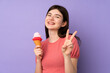 © luismolinero - Young Ukrainian teenager girl holding a cornet ice cream over isolated purple background smiling and showing victory sign