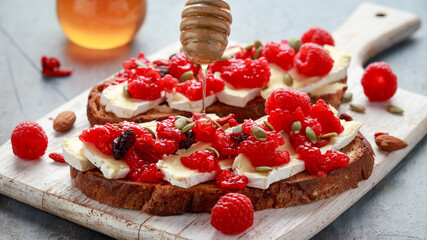 Raspberry and brie sourdough bread toast with pumpkin seeds and drizzled with honey