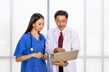 Happy Asian male and female medical doctor standing and discussing about case with laptop computer