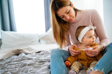 Wall Mural - Mother measuring temperature of her ill kid. Sick child with high fever, mother holding thermometer.