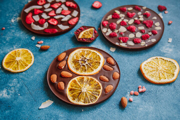 Wall Mural - Diet dark chocolate without sugar based on cocoa and stevia with the addition of freeze-dried berries, nuts and fruits. Top view on blue background