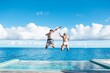 © Scopio - Two person jumping on pool