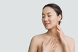 © Асель Иржанова - Skin care. An Asian woman with a beautiful face touches a healthy skin portrait. Beautiful smiling Asian girl model with natural makeup moisturized skin on white background copy space