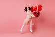© Look! - Full length shot of carefree girl holding heart shaped balloons. Indoor photo of ginger woman dancing in valentine's day.