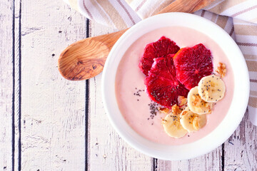Wall Mural - healthy blood orange and banana smoothie bowl with walnuts and chia seeds. top down view table scene