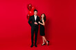 © Look! - Full length shot of couple in black clothes celebrating anniversary. Smiling man with valentine balloons hugs girlfriend.