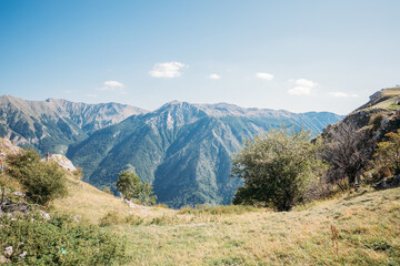 Poster - Mesmerizing shot of mountains with green bushes and trees under the clear sky