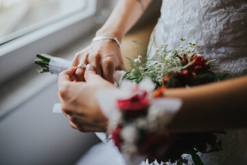 Wall Mural - Selective shot of the bride's hands showing her wedding ring and holding bouquet in her hand