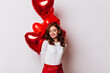 © Look! - Shy ginger girl posing in valentine's day. Studio photo of attractive woman with balloons isolated on white.