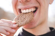 © Bernat - Happy young man eating cookie while smiles