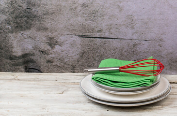 Plates with kitchen towels and cooking utensils on a wooden table with