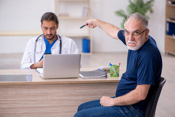 Wall Mural - Old male patient visiting young male doctor