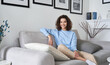 © insta_photos - Happy young pretty hispanic woman looking at camera sitting on sofa at cozy home. Happy cheerful casual teen girl, female model posing indoors, relaxing on couch in modern apartment, portrait.