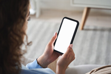 Young woman or teen girl hands holding smart phone with mockup white blank display, empty screen for social media app ads at home. Mobile applications technology concept, over shoulder close up view.