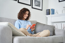 Happy Hispanic Teen Girl Holding Cell Phone Using Smartphone Device At Home. Smiling Young Latin Woman Blogger Subscribing New Social Media, Buying In Internet, Ordering Products Online In Apps.