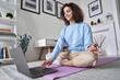 © insta_photos - Happy fit young woman using laptop computer watching online yoga lesson, fitness video class, learning virtual meditation training tutorial, doing exercise, feeling no stress, peace of mind at home.