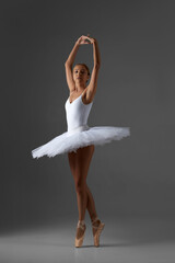Wall Mural - graceful ballerina in white tutu and pointe shoes dancing on gray background