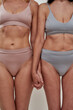 © Svitlana - Cropped shot of aged women in underwear holding hands together while posing half naked isolated over light background