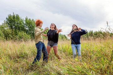 Summer holidays vacation happy people concept. Group of three friends boy and two girls dancing and having fun together outdoors. Picnic with friends on road trip in nature