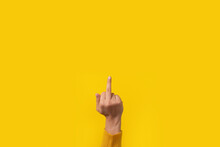 Hand gesture, fuck you symbol, middle finger sign over yellow background
