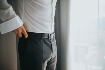 Canvas Print - Closeup shot of a male hand correcting his belt - wedding preparation