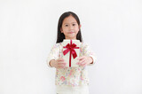Fototapeta Na ścianę - Little asian kid girl give you a gift box on white background. Happy new year and Merry christmas concept. Focus at child face