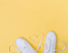 White Sneackers With Heart Shaped Laces On Yellow Background. Love Concept. Blogging Content. Female Teenager Sporty Casual Footwear.