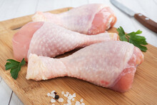 Raw Chicken Drumsticks With Parsley And Spices On A Wooden Cutting Board.