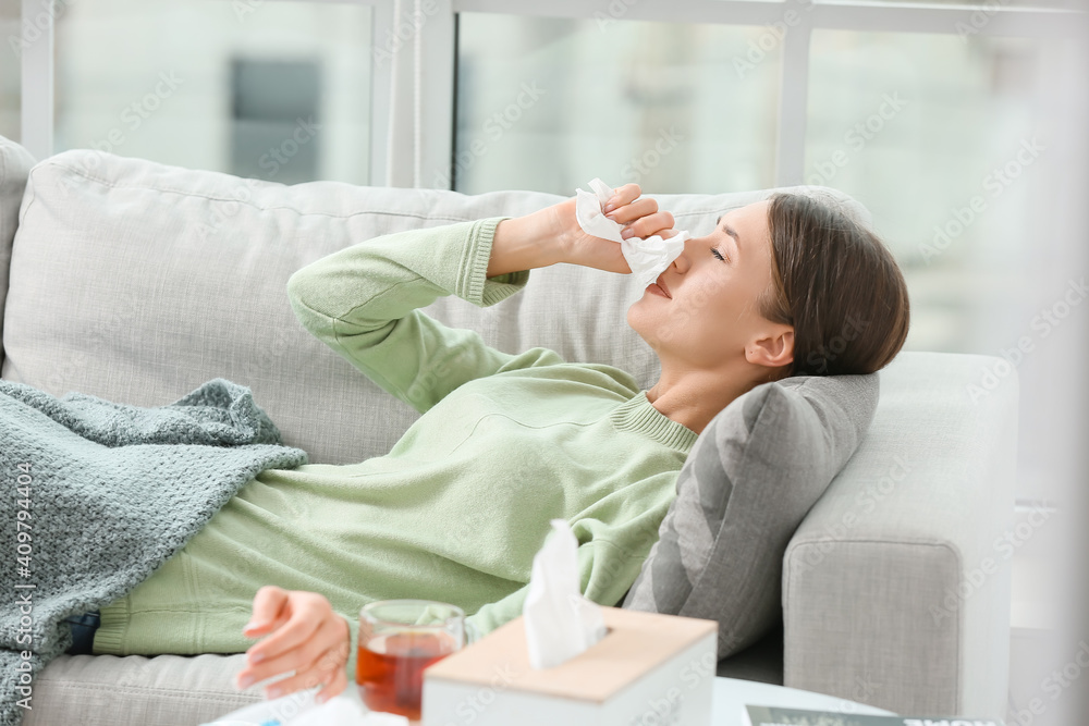 Sick young woman lying on sofa at home